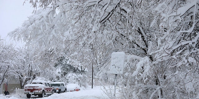 Street signs are covered in snow in north Flagstaff, Ariz., Friday, Nov. 29, 2019. A powerful storm making its way east from California is threatening major disruptions during the year's busiest travel weekend, as forecasters warned that intensifying snow and ice could thwart millions across the country hoping to get home after Thanksgiving. 