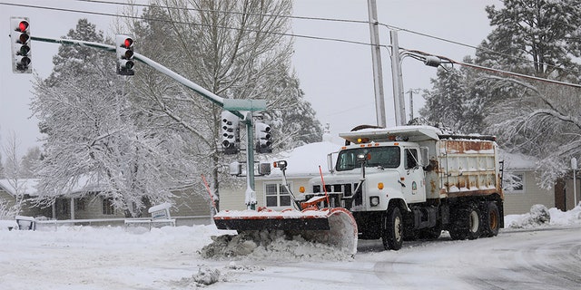 A city snowplow helps clear roads north of downtown Flagstaff, Ariz., Friday, Nov. 29, 2019. A powerful storm making its way east from California is threatening major disruptions during the year's busiest travel weekend, as forecasters warned that intensifying snow and ice could thwart millions across the country hoping to get home after Thanksgiving. The storm has already killed at least one person and shut down highways in the western U.S., stranding drivers in California and prompting authorities in Arizona to plead with travelers to wait out the weather before attempting to travel. 