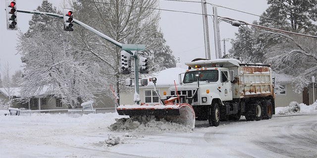 A city snowplow helps clear roads north of downtown Flagstaff, Ariz., Friday, Nov. 29, 2019. A powerful storm making its way east from California is threatening major disruptions during the year's busiest travel weekend, as forecasters warned that intensifying snow and ice could thwart millions across the country hoping to get home after Thanksgiving. The storm has already killed at least one person and shut down highways in the western U.S., stranding drivers in California and prompting authorities in Arizona to plead with travelers to wait out the weather before attempting to travel. 