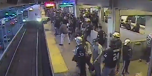 BART transportation supervisor John O'Connor pulls a man back onto the platform just before a train arrives at the Coliseum Station in Oakland, Calif. on Sunday.
