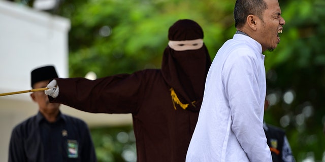 Aceh Ulema Council (MPU) member Mukhlis bin Muhammad reacts as he is whipped in public. (Photo by CHAIDEER MAHYUDDIN / AFP) (Photo by CHAIDEER MAHYUDDIN/AFP via Getty Images)