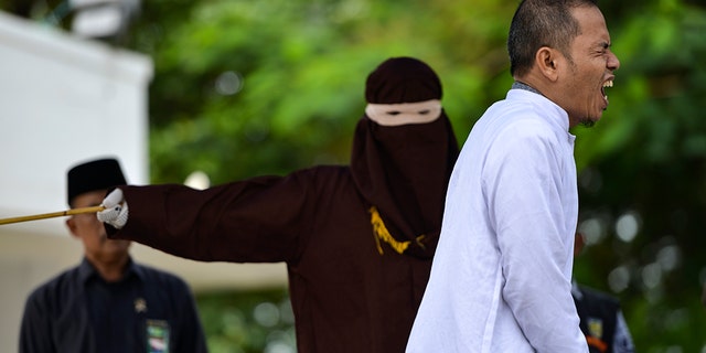 Aceh Ulema Council (MPU) member Mukhlis bin Muhammad reacts as he is whipped in public. (Photo by CHAIDEER MAHYUDDIN / AFP) (Photo by CHAIDEER MAHYUDDIN/AFP via Getty Images)