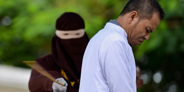 Aceh Ulema Council (MPU) member Mukhlis reacts as he is whipped in public by a member of the Sharia police in Banda Aceh on October 31, 2019.