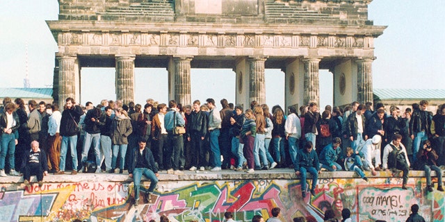 People standing on the Berlin Wall in front of the Brandenburg Gate in November 1989. (AP Photo, File)