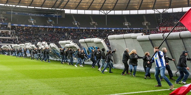 Fans tearing down the symbolic wall at the stadium in Berlin on Saturday. (Andreas Gora/dpa via AP)