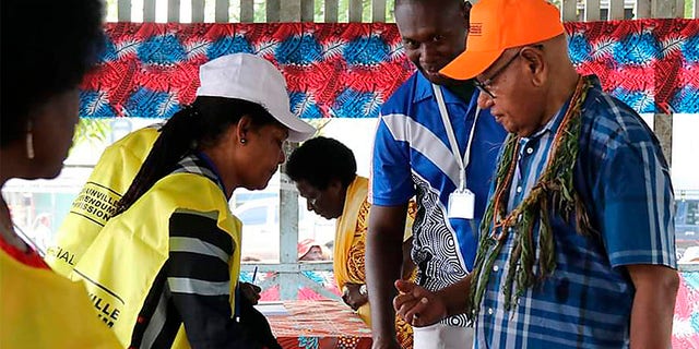 John Momis, right, president of the Autonomous Region of Bougainville, prepares to vote in Buka, Papua New Guinea, Saturday in a historic referendum to decide if they want to become the world's newest nation by gaining independence from Papua New Guinea. (Post Courier via AP)