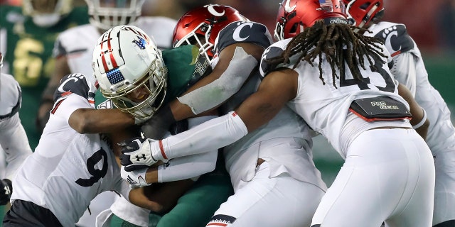 South Florida's Bryce Miller is wrapped up by Cincinnati defenders during the second half of an NCAA college football game, Saturday, Nov. 16, 2019, in Tampa, Fla. Cincinnati won 20-17. (AP Photo/Mike Carlson)