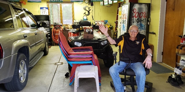 Andrew Slavonic poses in his garage with his gifted beer fridge in the back. 