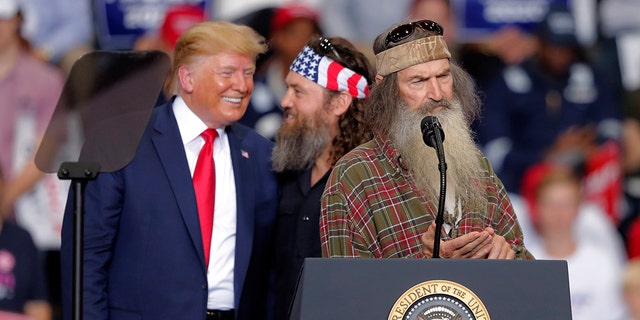 President Donald laughs with Willie Robertson, of the reality TV series Duck Dynasty, and Phil Roberston, the family patriarch, right, at a campaign rally in Monroe, La., Wednesday, Nov. 6, 2019. (Associated Press)