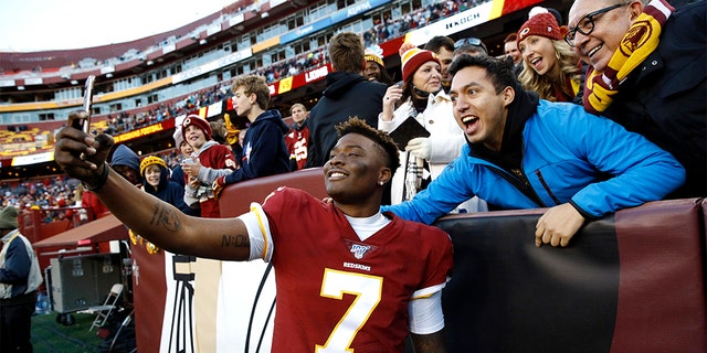Washington Redskins quarterback Dwayne Haskins takes selfies with fans during the second half of an NFL football game against the Detroit Lions, Sunday, Nov. 24, 2019, in Landover, Md. The Redskins won 19-16.