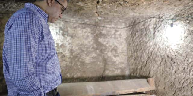 Egypt's Antiquities Minister Khaled el-Anany examines a coffin in the Saqqara necropolis.