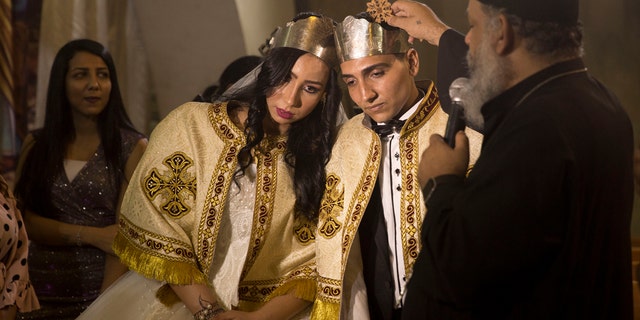 In this June 15, 2019, photo, a Coptic priest blesses an Egyptian couple during their wedding in St. Samaan’s Church, in the predominantly Christian Manshiyat Nasser area of Cairo (AP Photo/Maya Alleruzzo)