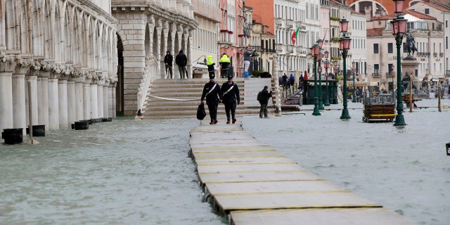 Two police officers walk on a gangway in flooded Venice, Italy, Sunday, Nov. 17, 2019.