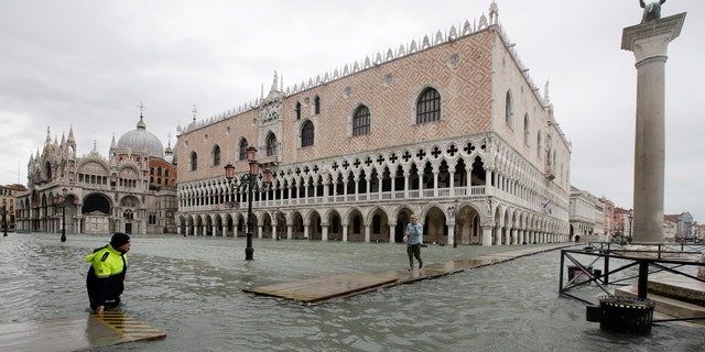 A woman arrives in St. Mark's Square on a gangway, in spite of a ban, in Venice, Italy, Sunday, Nov. 17, 2019.