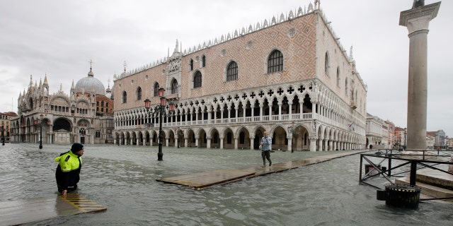 A woman arrives in St. Mark's Square on a gangway, in spite of a ban, in Venice, Italy, Sunday, Nov. 17, 2019.