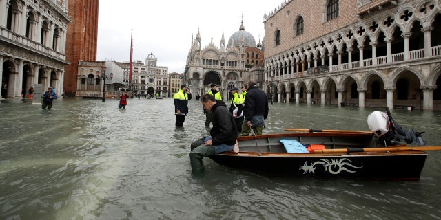 A man sits on a small boat in a flooded St.Mark square in Venice, Italy on Sunday.