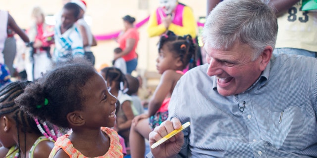 Franklin Graham helps a girl unpack her shoe box gift in Belize. Each Operation Christmas Child shoebox gift is packed with items such as toys, hygiene kits and school supplies.