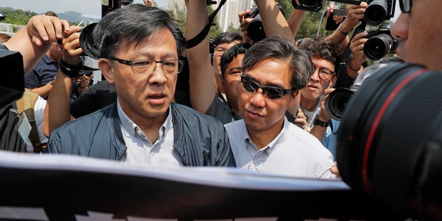 In this Aug. 12, 2019, photo, pro-Beijing lawmaker Junius Ho, left, attends a demonstration of an anti-riot vehicle equipped with water cannon at the Police Tactical Unit Headquarters in Hong Kong.