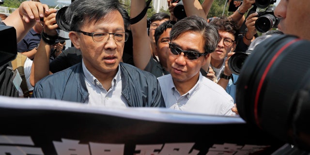 In this Aug. 12, 2019, photo, pro-Beijing lawmaker Junius Ho, left, attends a demonstration of an anti-riot vehicle equipped with water cannon at the Police Tactical Unit Headquarters in Hong Kong.
