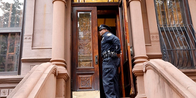 A New York City Police officer stands in the doorway of the building where the bodies were found.