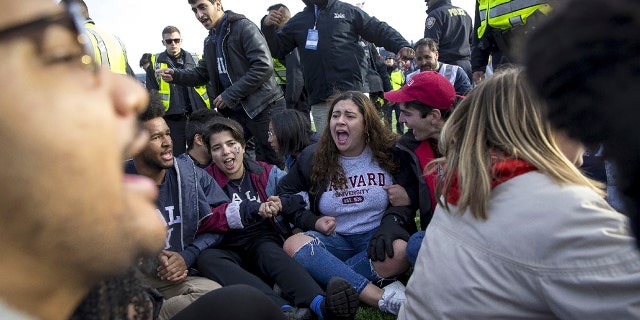 Harvard and Yale students protest during halftime of the NCAA college football game between Harvard and Yale at the Yale Bowl in New Haven, Conn., on Nov. 23, 2019. (Nic Antaya/The Boston Globe via AP)