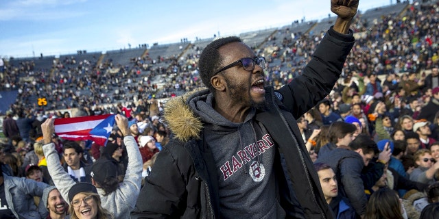 In this Saturday, Nov. 23, 2019, photo, Harvard and Yale students protest during halftime of the NCAA college football game between Harvard and Yale at the Yale Bowl in New Haven, Conn. Officials say 42 people were charged with disorderly conduct after the protest interrupted the game. (Nic Antaya/The Boston Globe via AP)