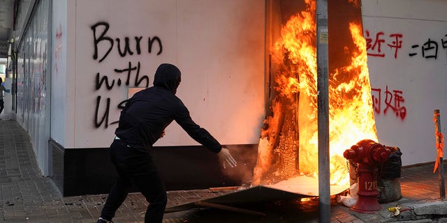 A protester sets fire to the cardboards outside the Bank of China branch during a protests in the Central district of Hong Kong, Monday, Nov. 11, 2019.