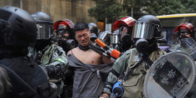 A protester is detained in Central district of Hong Kong on Monday, Nov. 11, 2019. A Hong Kong protester was shot by police Monday in a dramatic scene caught on video as demonstrators blocked train lines and roads during the morning commute. (AP Photo/Kin Cheung)