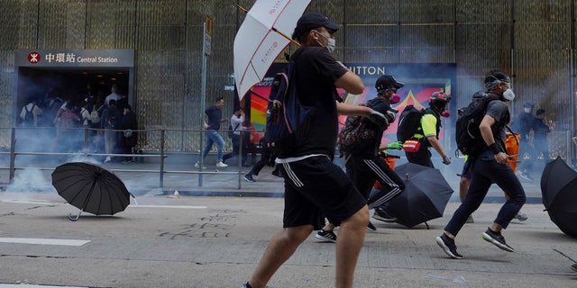 Pro-democracy protesters and people run away from tear gas fired by riot police during a rally in Central in Hong Kong, Tuesday, Nov. 12, 2019.