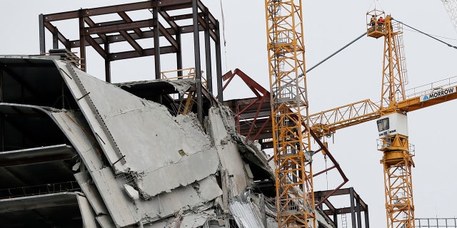 Workers begin the process of preparing the two unstable cranes for implosion at the collapse site of the Hard Rock Hotel, which underwent a partial, major collapse while under construction last Sat., Oct., 12, in New Orleans, Friday, Oct. 18, 2019. Plans have been pushed back a day to bring down two giant, unstable construction cranes in a series of controlled explosions before they can topple onto historic New Orleans buildings, the city's fire chief said Friday, noting the risky work involved in placing explosive on the towers. (AP Photo/Gerald Herbert)
