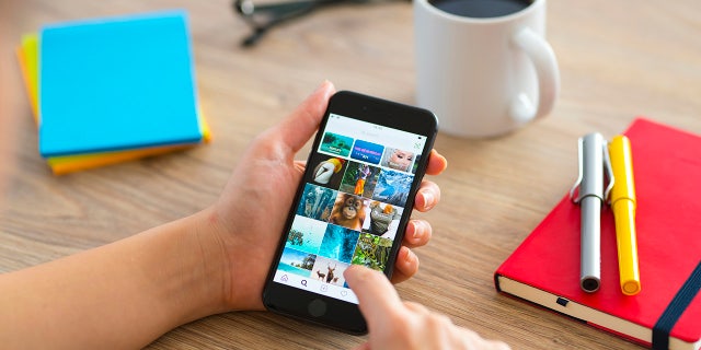 Woman using smartphone on a wooden desk. 