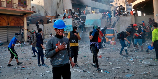 Protesters reacting to tear gas fired by riot police during fighting in Baghdad on Sunday.