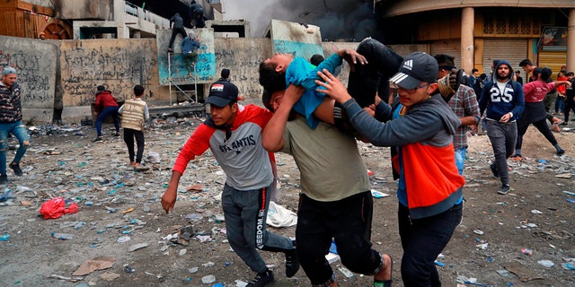 A wounded protester is carried to receive first aid during clashes in Baghdad Thursday. (AP Photo/Khalid Mohammed)