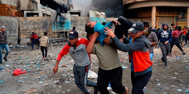 Political News: A wounded protester is carried to receive first aid during clashes in Baghdad Thursday. (AP Photo/Khalid Mohammed)