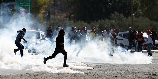Palestinian demonstrators run from tear gas fired by Israeli troops during the protest against the U.S. announcement that it no longer believes Israeli settlements violate international law.