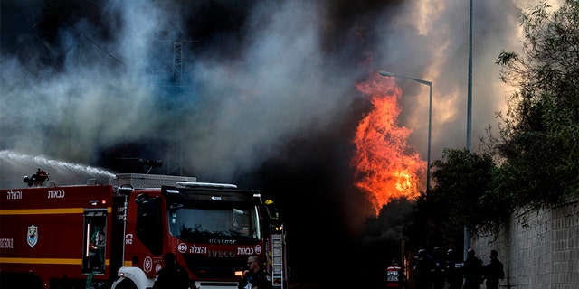 Firefighters deploy after a factory hit by a rocket caught fire in Sderot Tuesday.