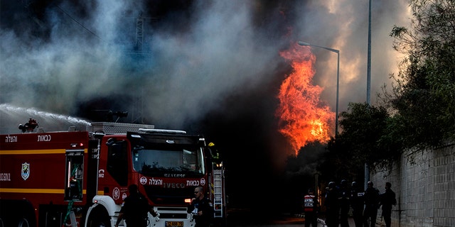Firefighters deploy after a factory hit by a rocket caught fire in Sderot Tuesday.