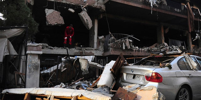 A Syrian official checks the damage of a building targeted by Israeli missile strikes in Damascus early Tuesday.