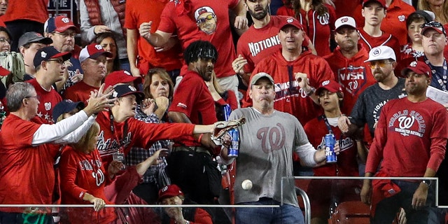 While holding two Bud Light beer cans, baseball fan, Jeff Adams, is hit in the chest with the home run ball hit by Yordan Alvarez #44 of the Houston Astros (not pictured) in the second inning during Game 5 of the 2019 World Series between the Houston Astros and the Washington Nationals at Nationals Park on October 27, 2019 in Washington, DC. (Photo by Patrick Smith/Getty Images)