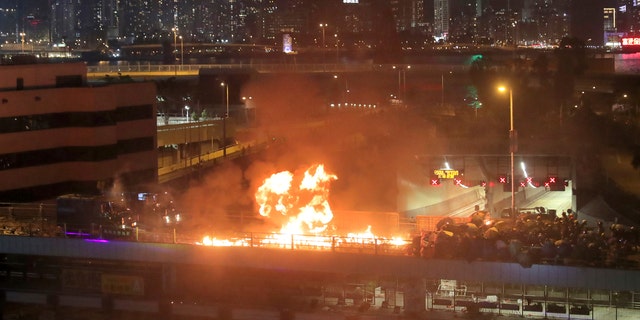 Protestors hurl molotov cocktails as armored police vehicles approach their barricades on a bridge over a highway leading to the Cross Harbour Tunnel in Hong Kong, on Sunday.