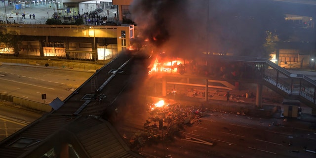 A fire burns on a bridge occupied by protestors over a highway leading to the Cross Harbour Tunnel in Hong Kong, Sunday, Nov. 17, 2019.