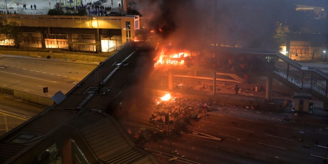 A fire burns on a bridge occupied by protestors over a highway leading to the Cross Harbour Tunnel in Hong Kong, Sunday, Nov. 17, 2019.