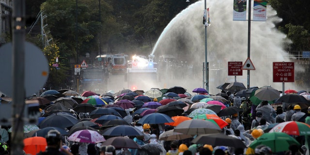 Protesters react as an armored police vehicle sprays water during a confrontation at Hong Kong Polytechnic University in Hong Kong, Sunday, Nov. 17, 2019.