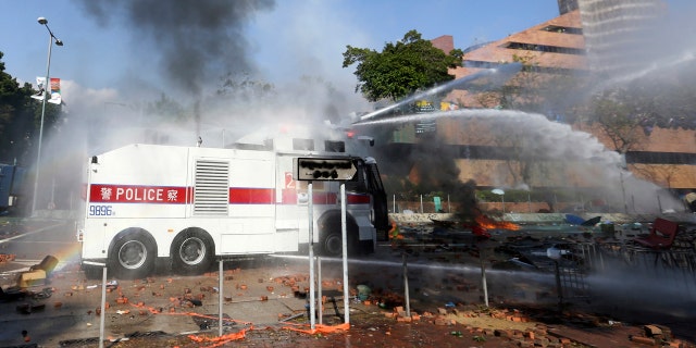 An armored police vehicle sprays water during a confrontation with protesters at the Hong Kong Polytechnic University in Hong Kong, Sunday, Nov. 17, 2019.