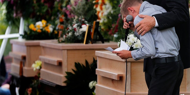 A boy pauses as he speaks next to the coffins of Dawna Ray Langford, 43, and her sons Trevor, 11, and Rogan, 2, who were killed by drug cartel gunmen, during the funeral at a family cemetery in La Mora, Sonora state, Mexico, Thursday, Nov. 7, 2019.(AP Photo/Marco Ugarte)