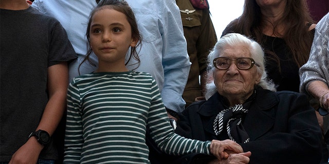 Melpomeni Dina holding the hand of an Israeli girl during a reunion at the Yad Vashem Holocaust memorial in Jerusalem on Sunday.