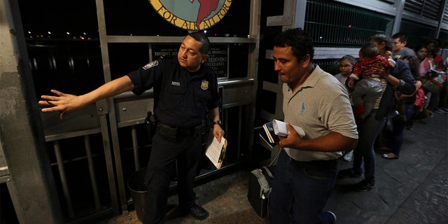 A U.S. border patrol officer directing a Nicaraguan migrant family over International Bridge 1 from Nuevo Laredo, Mexico, into Laredo, Texas, for an interview with immigration officials this pas September. (AP Photo/Fernando Llano, File)