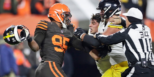 Cleveland Browns defensive end Myles Garrett, left, gets ready to hit Pittsburgh Steelers quarterback Mason Rudolph, second from left, with a helmet during the second half of an NFL football game Thursday, Nov. 14, 2019, in Cleveland. 
