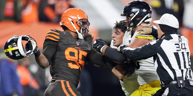 Cleveland Browns defensive end Myles Garrett, left, gets ready to hit Pittsburgh Steelers quarterback Mason Rudolph, second from left, with a helmet during the second half of an NFL football game Thursday, Nov. 14, 2019, in Cleveland. The Browns won 21-7. (AP Photo/Ron Schwane)