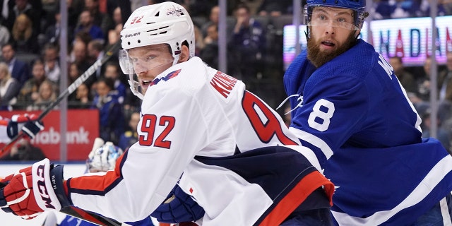 Washington Capitals center Evgeny Kuznetsov (92) works against Toronto Maple Leafs defenseman Jake Muzzin (8) during the first period of an NHL hockey game Tuesday, Oct. 29, 2019, in Toronto. (Hans Deryk/The Canadian Press via AP)